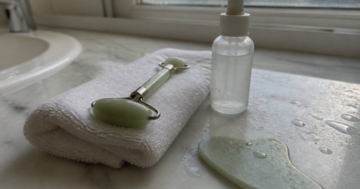 Jade-Roller auf einem Handtuch neben Serum